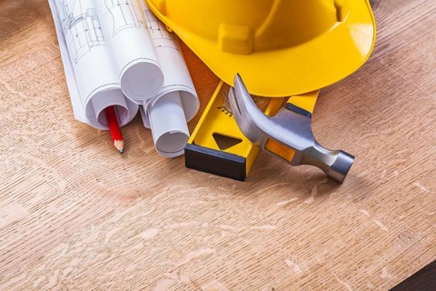 Hardhat level hammer blueprints pencil on wooden boards