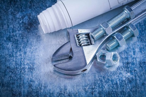 Steel adjustable spanner screw-nuts bolts and blueprints on scratched metallic background