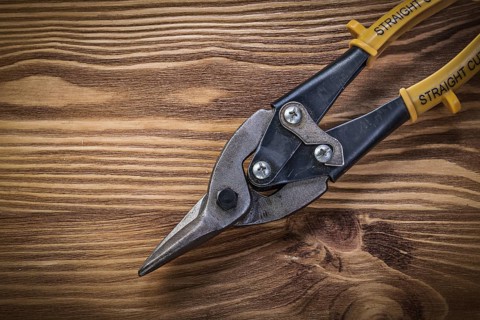 Tin snips on vintage wooden board top view construction concept