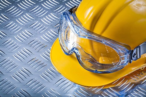 Protective glasses building helmet on grooved metal sheet construction concept