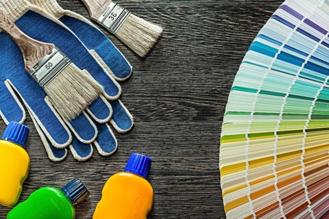 Safety gloves paint brushes bottles pantone fan on wooden board