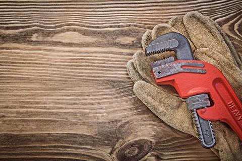 Pair of leather protective gloves monkey wrench on wood board construction concept