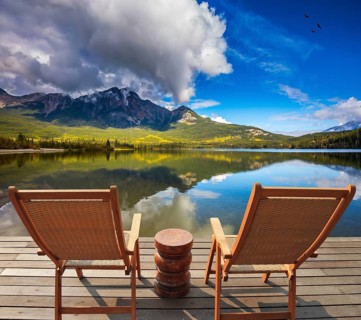 Two comfortable wooden sun beds for tourists, interconnected table. Pyramid Mountain reflected in