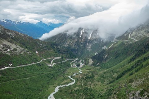 Situation on Furka pass on a cloudy summer day. View into the Rhone valley with mountain passes.