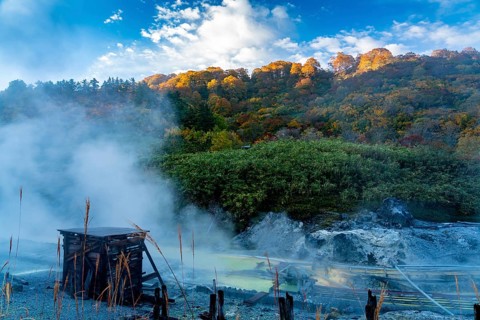 View in Tamagawa onsen in the morning with sunlight shine on the colorful autumn foliage forest on