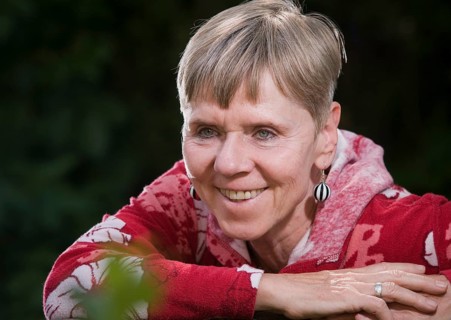 Portrait of an elderly woman on a park bench in summer with her upper body turned backwards over