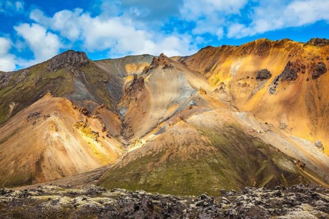 Multi-colored mountains from rhyolite are lit with the July sun. Travel to Iceland in the summer.