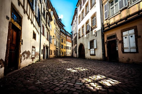Narrow alley in the old town of Colmar with cobblestones and historic buildings under a blue sky in