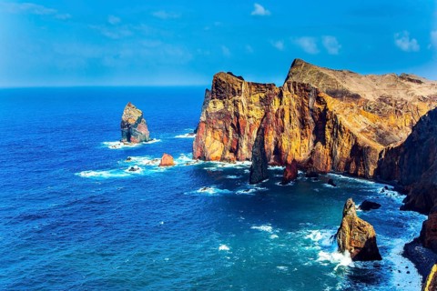 Island in the Atlantic. The coast of the island of Madeira - red rocks, azure surf. The blinding
