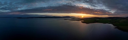 Sunset with cloud band on the coast of Scapa Flow with view to the island of Hoy, drone shot,