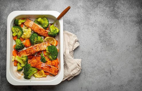 Top view of healthy baked fish salmon steaks, broccoli, cauliflower, carrot in casserole dish on