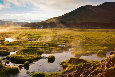 Above the source of thermal water steam rises. White nights in Iceland. Sunrise Park