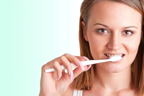 Closeup of young woman with a tooth brush on her hands, about to brush her teeth