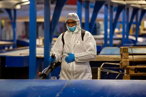 Sofia, Bulgaria - 7 April, 2020: Worker sprays disinfectant outside of ? food market against the