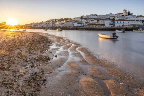 Sunrise with view over a beach and harbour basin at low tide. Panorama picture of a historic old