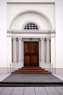 The entrance of a newly built and modern church with an entrance door with a round arch and white