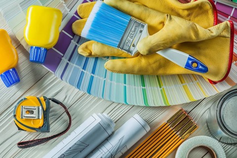 Paint brush in working gloves with any other construction tools on white wood boards