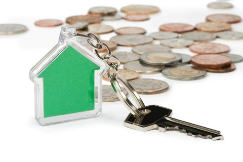 Coins and green house key ring. White isolated studio shot