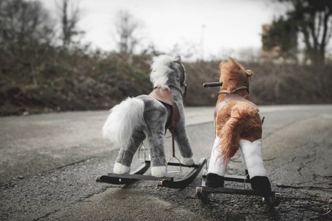 Abandoned rocking horses on the road. Concept of abandonment, loneliness, the end of childhood