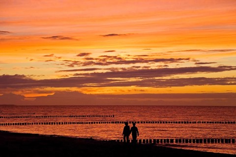 Couple talking a walk at the beach at sunset
