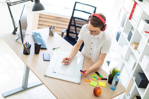 A young man in a white shirt and light jeans is working in a bright office. photo with depth of