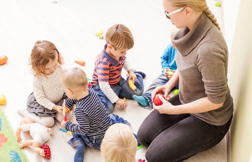 Children with teacher in kindergarten playing cooks