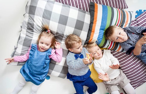 Cute little boys and girls lying on the pillows and playing in the kindergarten, top view