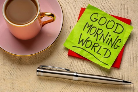 Good Morning world cheerful and positive memo - handwriting on a sticky note with cup of coffee