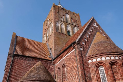Close-up of the historic church tower and building under a blue sky, krummhörn, east frisia,