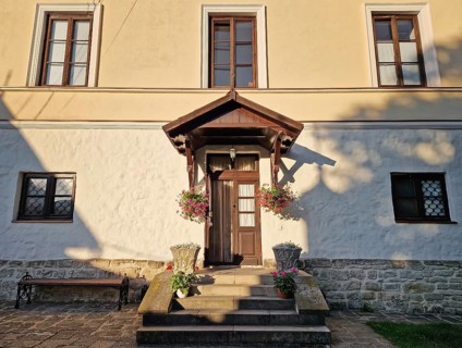 Rustic old building facade with porch and a charming wooden door, framed by two side windows and a