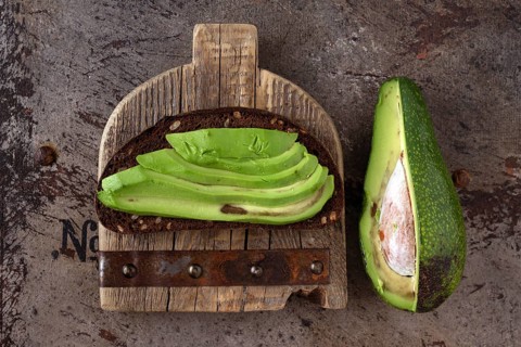 Avocado sandwich on wooden board, vintage iron background