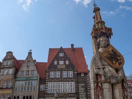 Historic old town with half-timbered houses and a large statue under a blue sky, Bremen, Germany