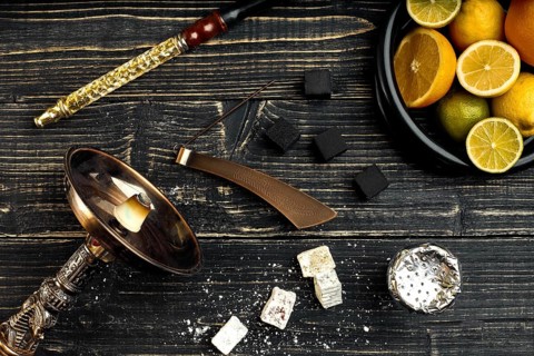 Stylish Smoking hookah and basket with lemon, lime and orange on wooden background. Top view. Flat