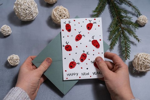 Reindeer fingerprints Sustainable Christmas preparation female hand holding handmade greeting cards