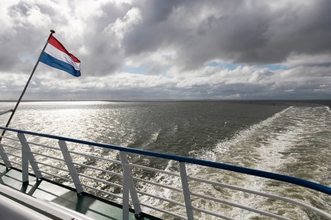 Wadden Sea with Dutch flag and wake as seen from the ferry