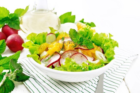 Radish, onion and orange salad with mint, vegetable oil and spices on lettuce in a plate on a towel