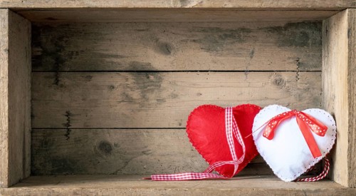 An image of two felt hearts on a wooden background