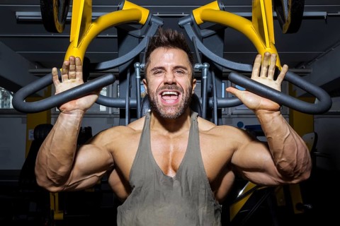 An image of a handsome bearded bodybuilding man doing chest workout