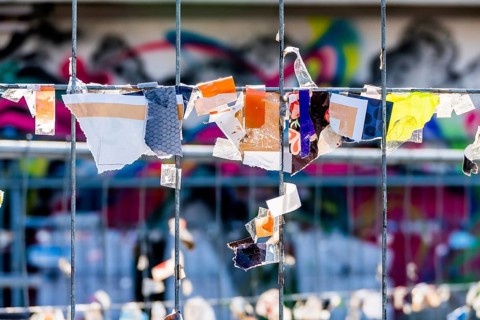 Scraps of paper against a wire fence, symbolising creativity, disorder, protest