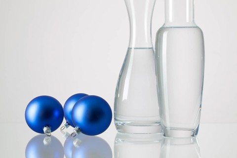 Two vases with clean water and Christmas decoration on a glass table