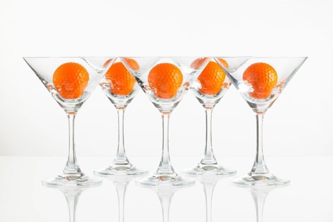 Five glasses of champagne and golf equipments on the glass desk