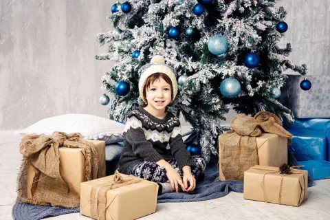 Christmas and New Year concept. A pretty girl in a white knitted hat and jumper sits on the floor