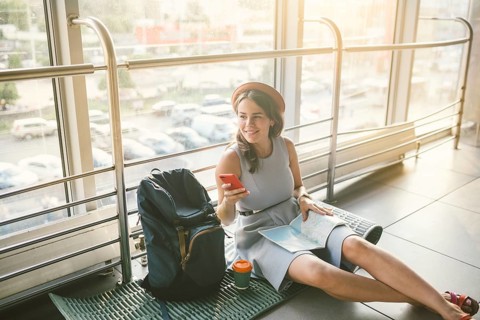 Theme of tourism and travel of young student. Beautiful young caucasian girl in dress and hat sits