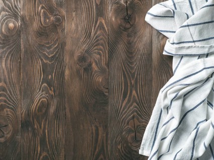 View from above on brown wooden table with linen kitchen towel or textile napkin. Blue tablecloth