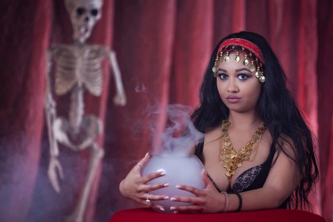 A fortune teller with an oriental look next to a skeleton and a fog vessel, studio shot, staged