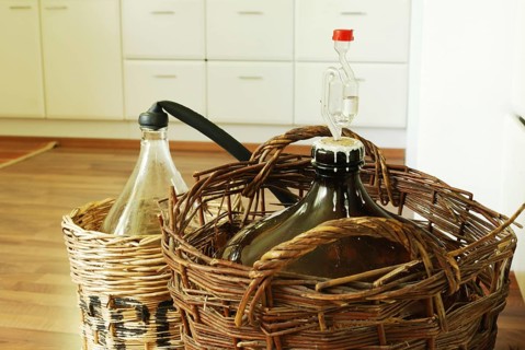 Bottles of homemade wine in wicker baskets