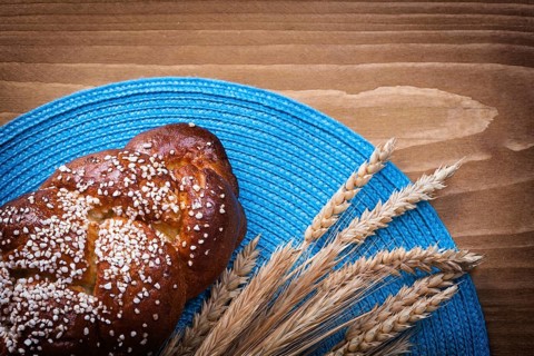 Sweet roll wheat rye ears with blue wattled cover on wooden board food and drink concept