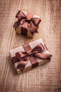 Two vintage gift boxes with brown bows on old wooden board