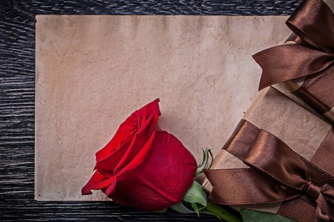 Vintage paper red expanded rose wrapped giftboxes on wooden board
