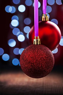 Two red christmas balls hanging on pink tape on old wooden table and blurred bokeh background